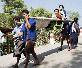 Porters carry a pilgrim down from Kyaiktiyo Pagoda